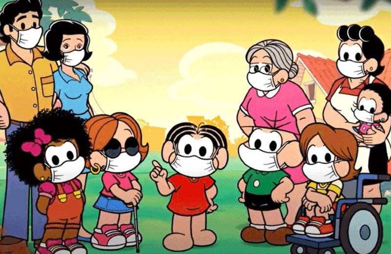 Foto dos personagens da Turma da Mônica para a campanha A importância da vacinação. Todos os personagens usam máscara e entre eles há dois com deficiência, um deficiente visual, com óculos e bengala, e outro deficiente físico, sentado numa cadeira de rodas